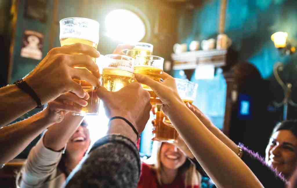 People raising pints of beer and saluting