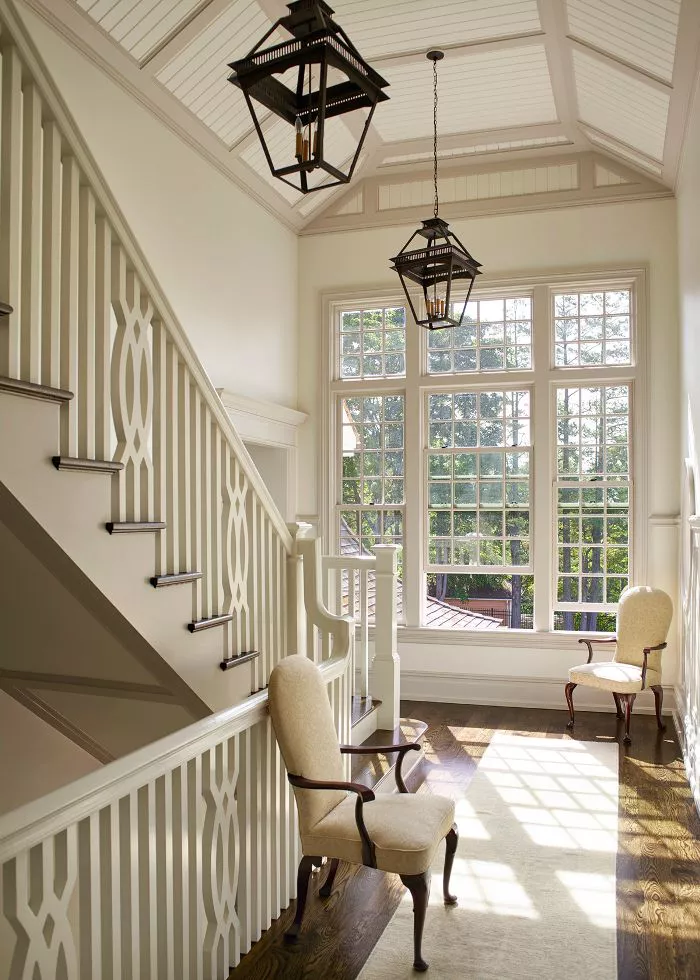 modern traditional grand staircase with large windows and black lantern pendant lights